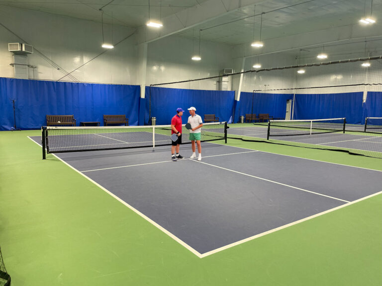 Players connecting beside the net at E.H. Pickleball Club